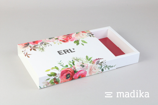 Die Schiebeschachtel mit Hohlwand greift bei der Bedruckung des Einlegers die Farben des Blumenmusters auf. Offene Schiebeschachtel mit Hohlwand und Blumenmuster