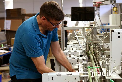 Die Faltschachtelklebemaschine wird eingerichtet, damit die nächsten Faltschachteln gefaltet und geklebt werden können. Faltschachtelherstellung an der Klebemaschine