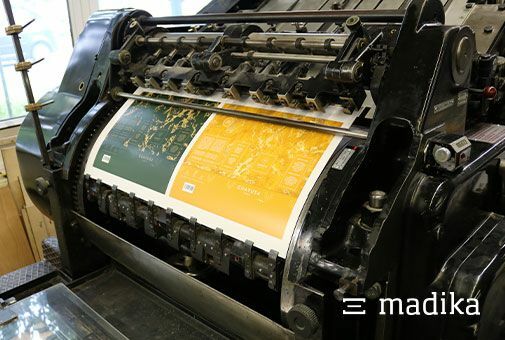 Zwei Faltschachteln (zu erkennen an den unterschiedlichen Farben) werden hier ausgestanzt. Stanzen zweier Faltschachteln an einer Stanzmaschine